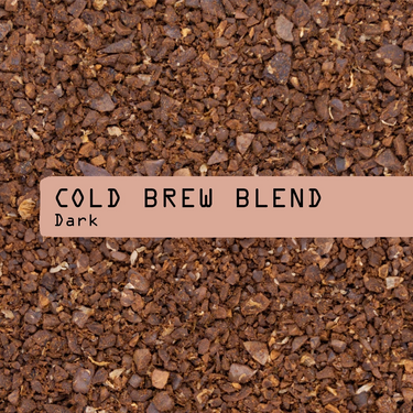 A close-up photo of dark brown cold brew coffee grounds with a horizontal muted peach label across the center reading 'COLD BREW BLEND. Dark'.