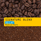 A coffee blend product photograph showing whole roasted coffee beans at the top, a bright yellow banner across the center reading 'SIGNATURE BLEND' and 'DECAF Medium/Dark', and ground coffee at the bottom.