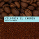 Coffee product photo showing whole roasted coffee beans at the top, ground coffee at the bottom, and a light blue label across the center reading 'COLOMBIA EL CARMEN Medium/Dark'.
