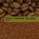 Coffee bean whole and ground close-up with a green label reading 'INDIA MONSOON MALABAR Dark'.