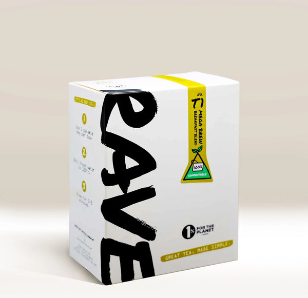 A white cardboard box of Rave tea, featuring bold black brushstroke lettering on the front, a yellow and green warning label, and yellow text accents, set against a warm beige background.